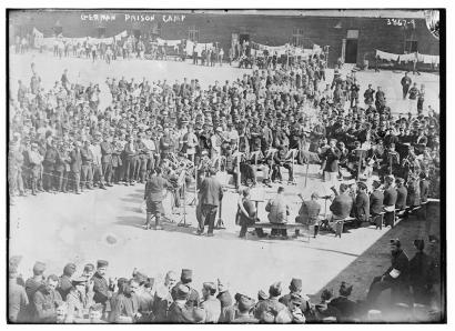 Black and white photograph of a large band standing in a circle playing on instruments for an even larger audience gathered around them