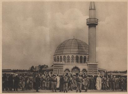 Sepia photograph of a crowd of people gathered in front of a domed mosque